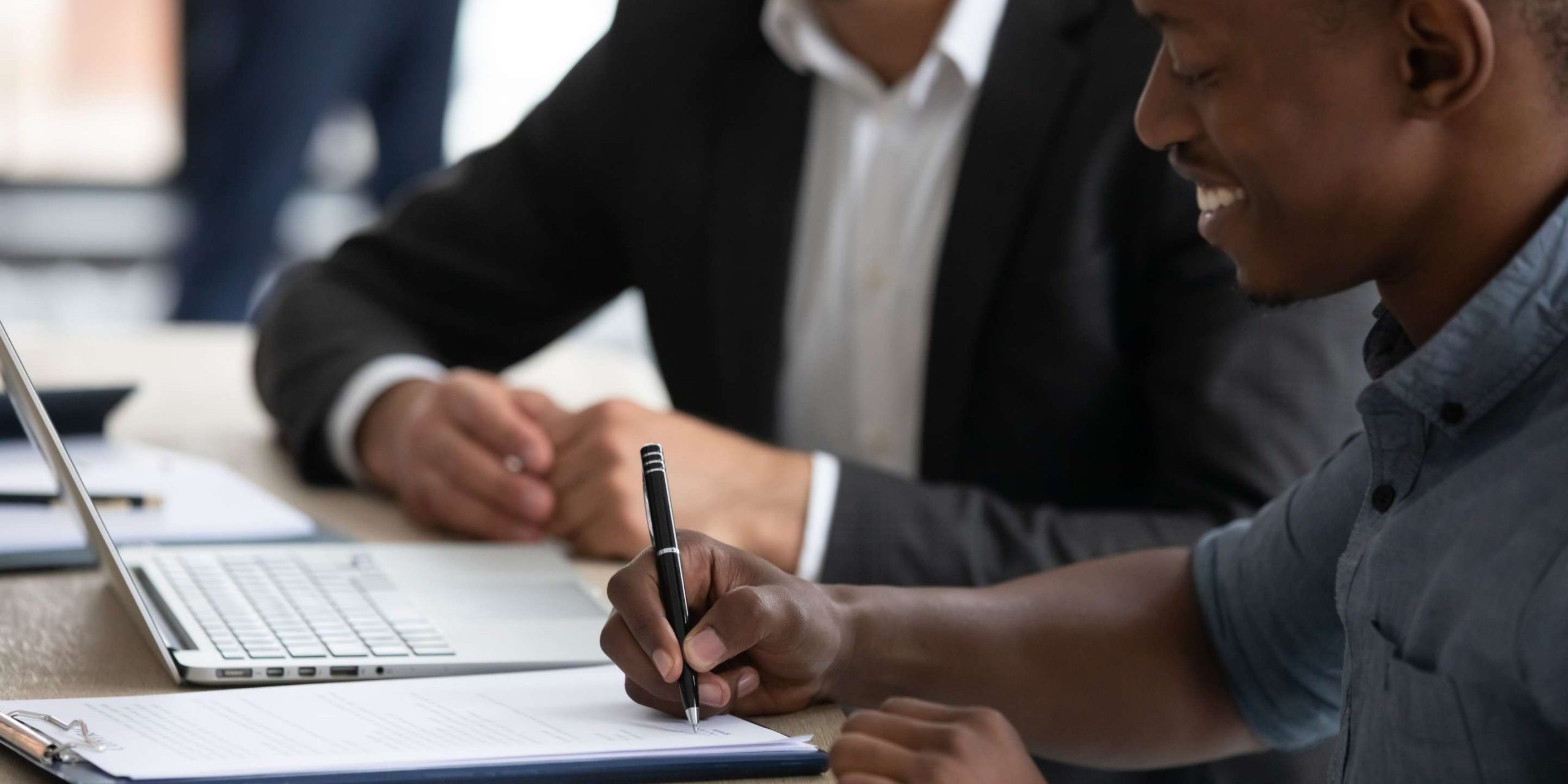 Gentleman signing contract all smiles next to his lawyer | The Importance of Written Contracts in Business and Tips for Negotiating Commercial Contracts in Kenya | Njaga & Co. Advocates commercial lawyers