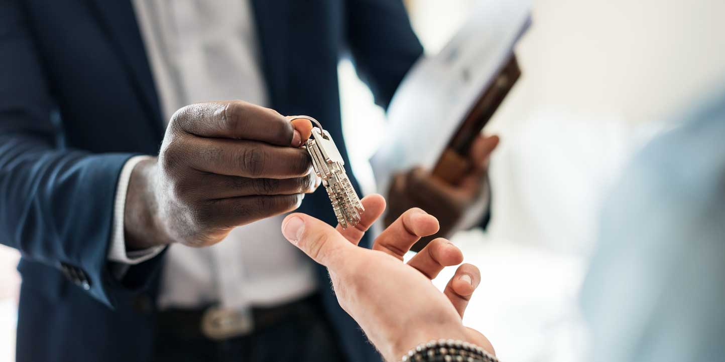 A professional handing over a house key to another person, symbolizing real estate transactions and property conveyancing | Legislative Framework Governing Real Estate Conveyancing in Kenya | Njaga & Co. Advocates legal articles
