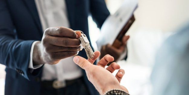 An African descent man handing over keys to a Caucasian man while holding documents in hand | The Best Forum for Instituting a Claim for Refund of Security Deposit from Your Landlord | General litigation lawyers in Nairobi | Njaga Advocates dispute resolution lawyers