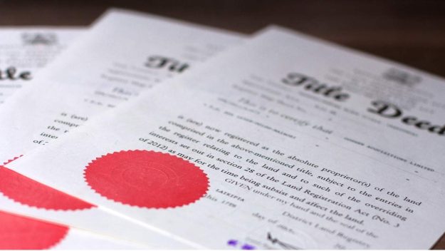 Title deed documents on a table | Resolving Disputes in Jointly Owned Property in Kenya: Legal Remedies under the Land Registration Act, 2012 | Real Estate lawyers in Nairobi | Njaga & Co. Advocates