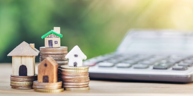 Taxes and Legal Costs Coins stacked in 4, with houses on them next to a calculator | A Comprehensive Guide to Taxes and Legal Costs When Buying Property in Kenya (Commercial & Non-Commercial) | Trusted Property lawyers in Kenya | Njaga & Co Advocates LLP Kenya