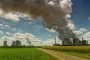 Industrial power plant emitting thick smoke into the sky, situated next to green farmland, symbolizing the contrast between industrial pollution and agriculture | Landmark Judgment on Climate Change, Carbon Markets, Offset Projects, Public Participation, and Community Land Rights in Kenya | ESG and climate change lawyer in Nairobi | Njaga & Co. Advocates LLP ESG law firm