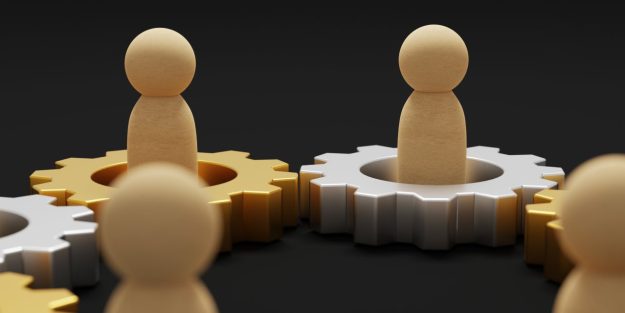 mergers and acquisitions Wooden figures standing in interlocking gold and silver gears| Mergers and Acquisitions in Kenya: A Comprehensive Overview | Corporate and commercial law firm in Nairobi | Njaga & Co. Advocates