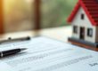 title deed on a clip board with a pen on it next to a house | A Comprehensive Guide to the Conversion of Titles in Kenya | Njaga & Co Advocates LLP real estate law firm
